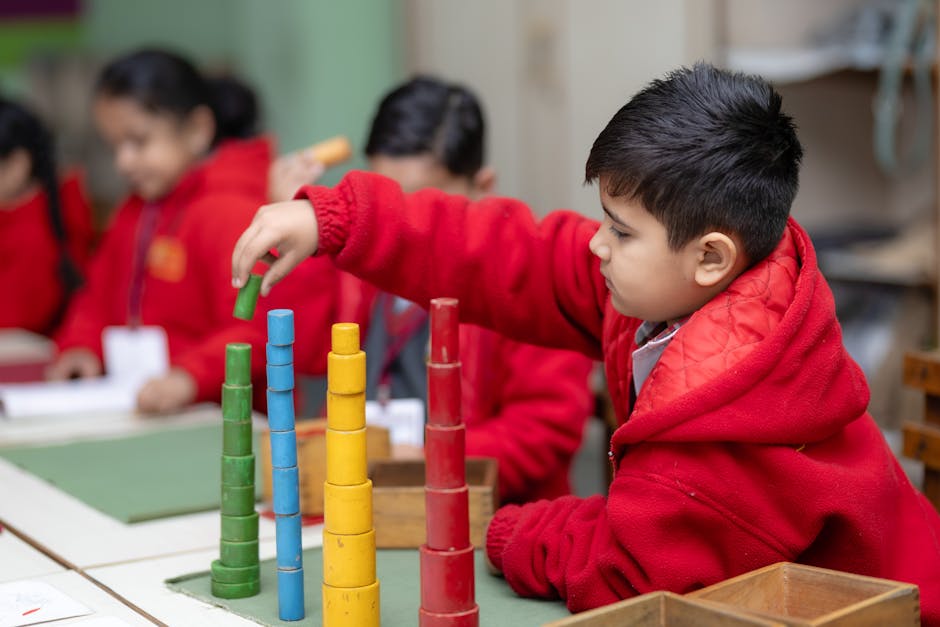 Boy in red jacket stacking colorful blocks in a creative classroom setting